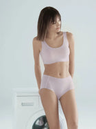 Woman wearing a lNuCloud Original Mid-Rise Brief Set Cream standing in front of a washing machine.