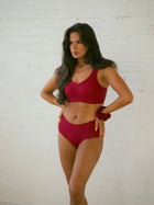 Woman wearing NuCloud Red Bra Set against a white brick wall.